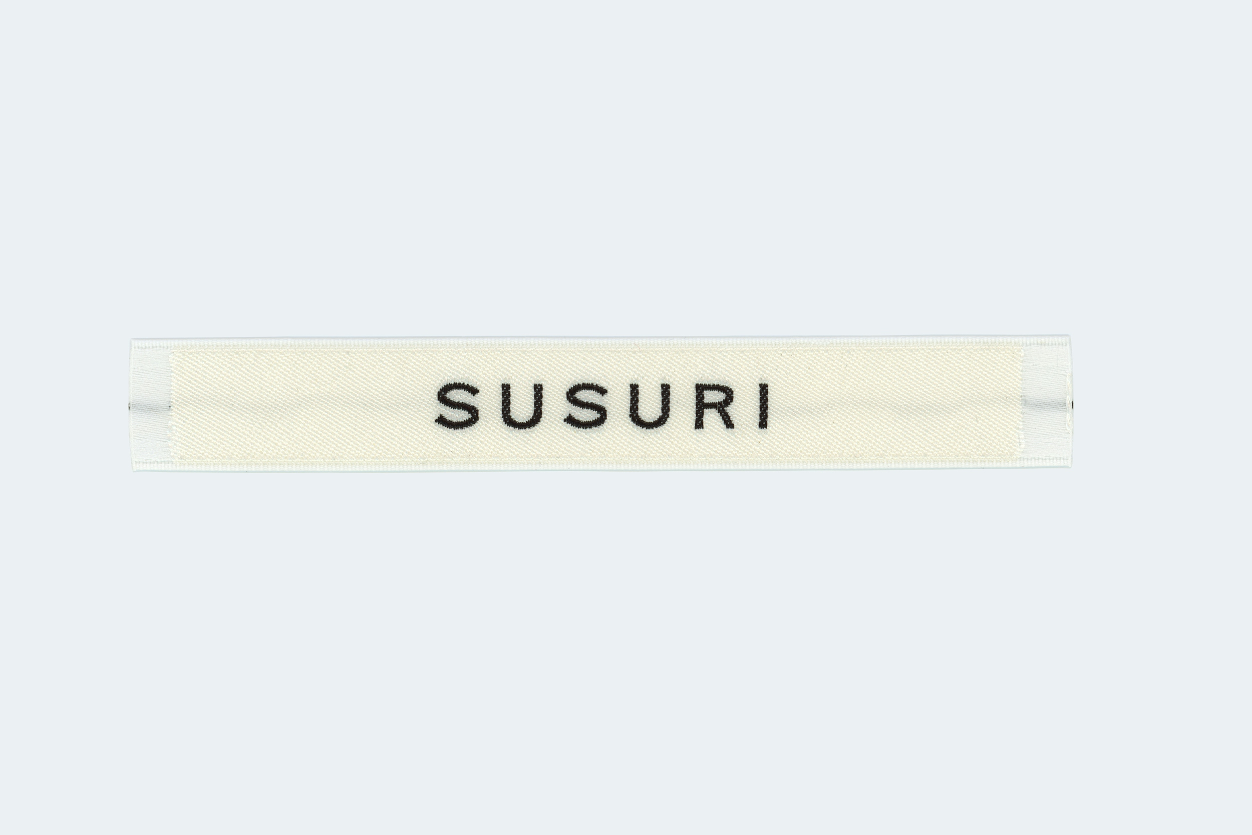 scanned cloth tag showing the SUSURI logo